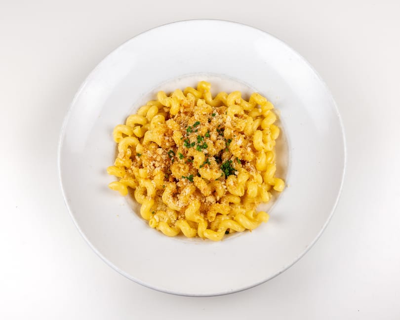 Creamy mac and cheese with cavatappi pasta, topped with golden breadcrumbs and fresh chives.