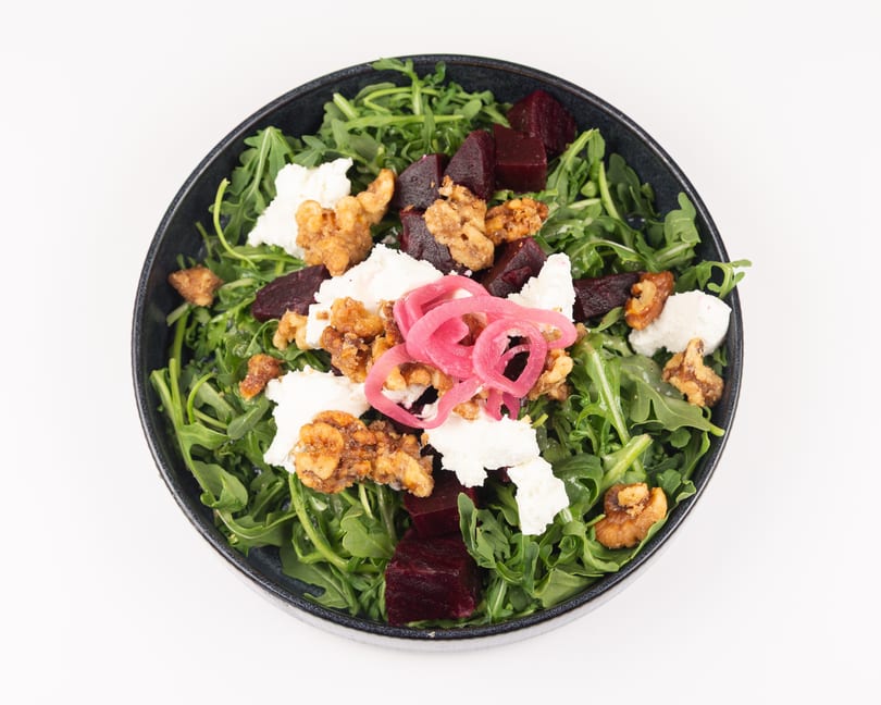 Vibrant arugula salad with beets, goat cheese, candied walnuts, and pickled onions.